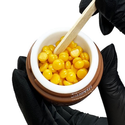 Compact white electric wax heater with a removable metal pot and lid, set on a plain studio background.