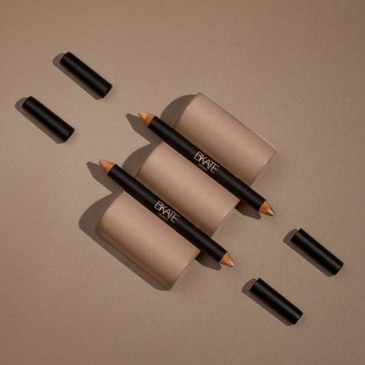 Dual-ended B'KATE brow highlighter pencil featuring a matte lifting shade and a shimmering champagne highlight, formulated as vegan and cruelty-free for brow bone enhancement.