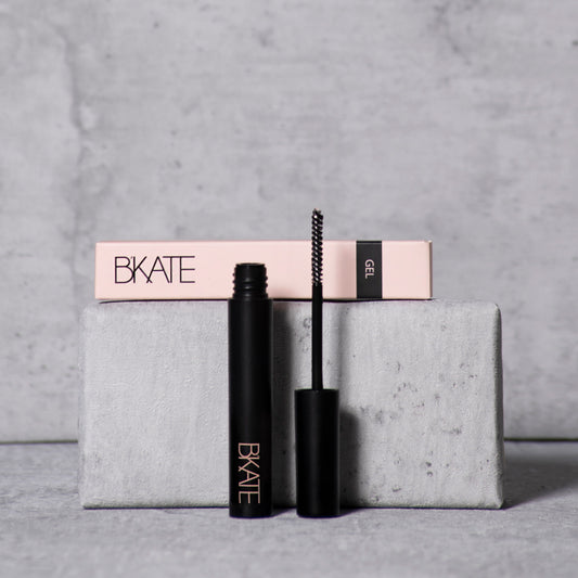 B'KATE brow gel tube next to its packaging box, featuring a fine spoolie brush designed to groom and set eyebrow hairs with a vitamin B5-enriched clear formula.