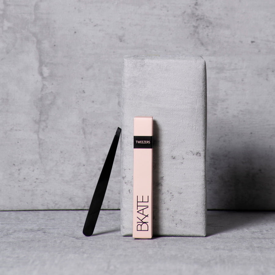 Sleek black B'KATE precision eyebrow tweezers with a delicate tapered point, designed for isolating and plucking short, fine brow hairs.