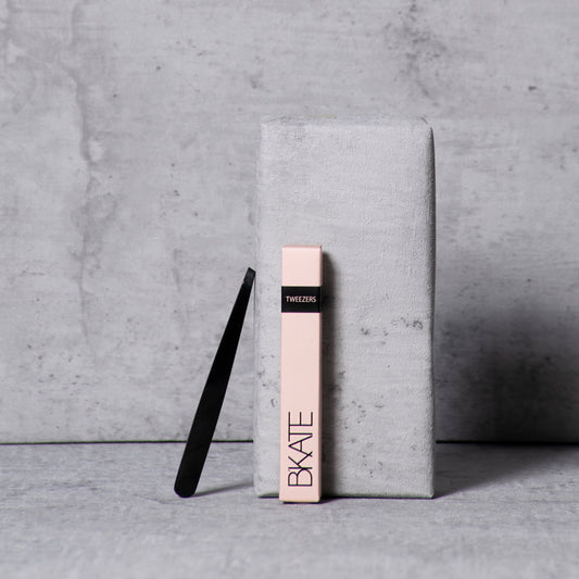 Sleek black B'KATE precision eyebrow tweezers with a delicate tapered point, designed for isolating and plucking short, fine brow hairs.