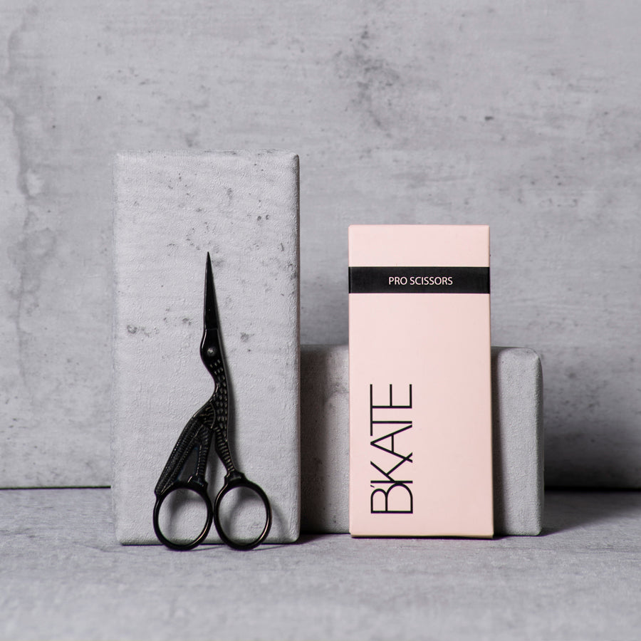 Sleek matte black titanium eyebrow trimming scissors featuring ultra-sharp, precise blades and an ergonomic handle design for accurate professional brow shaping.