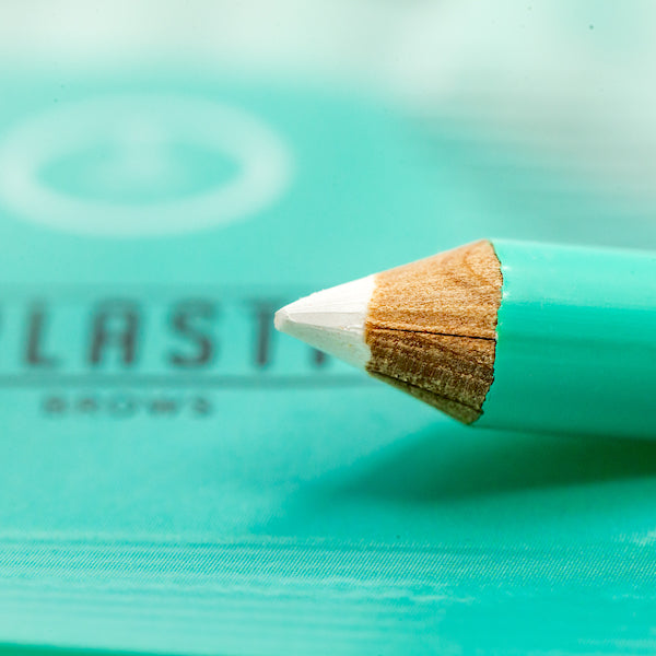 A white single-use Everlasting predraw brow pencil shown on a dark background displaying crisp white swatch marks for eyebrow mapping.