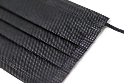 Medical-grade 3-ply blue disposable face mask in individual sterile plastic wrapping being pulled from a box, featuring soft earloops and fluid-resistant layers.
