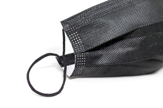 Medical-grade 3-ply blue disposable face mask in individual sterile plastic wrapping being pulled from a box, featuring soft earloops and fluid-resistant layers.