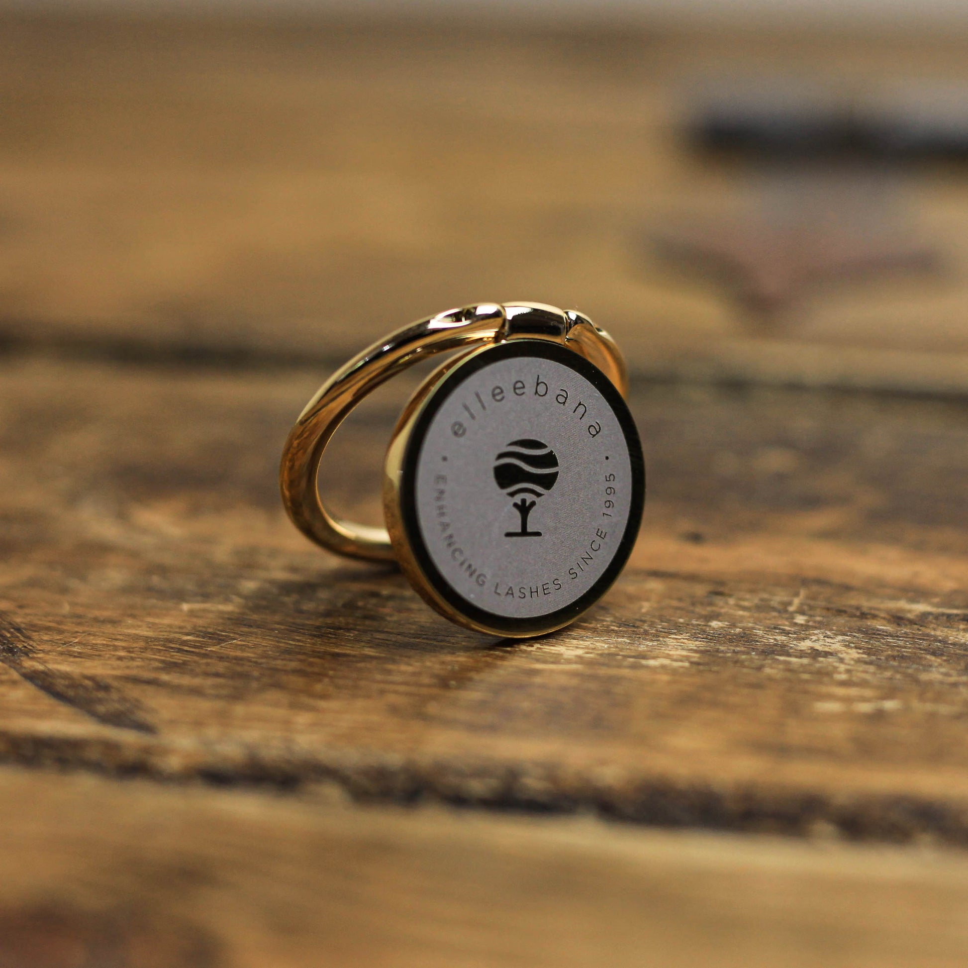 Branded smartphone phone grip and ring holder accessory attached to a phone, designed to secure devices during photography.