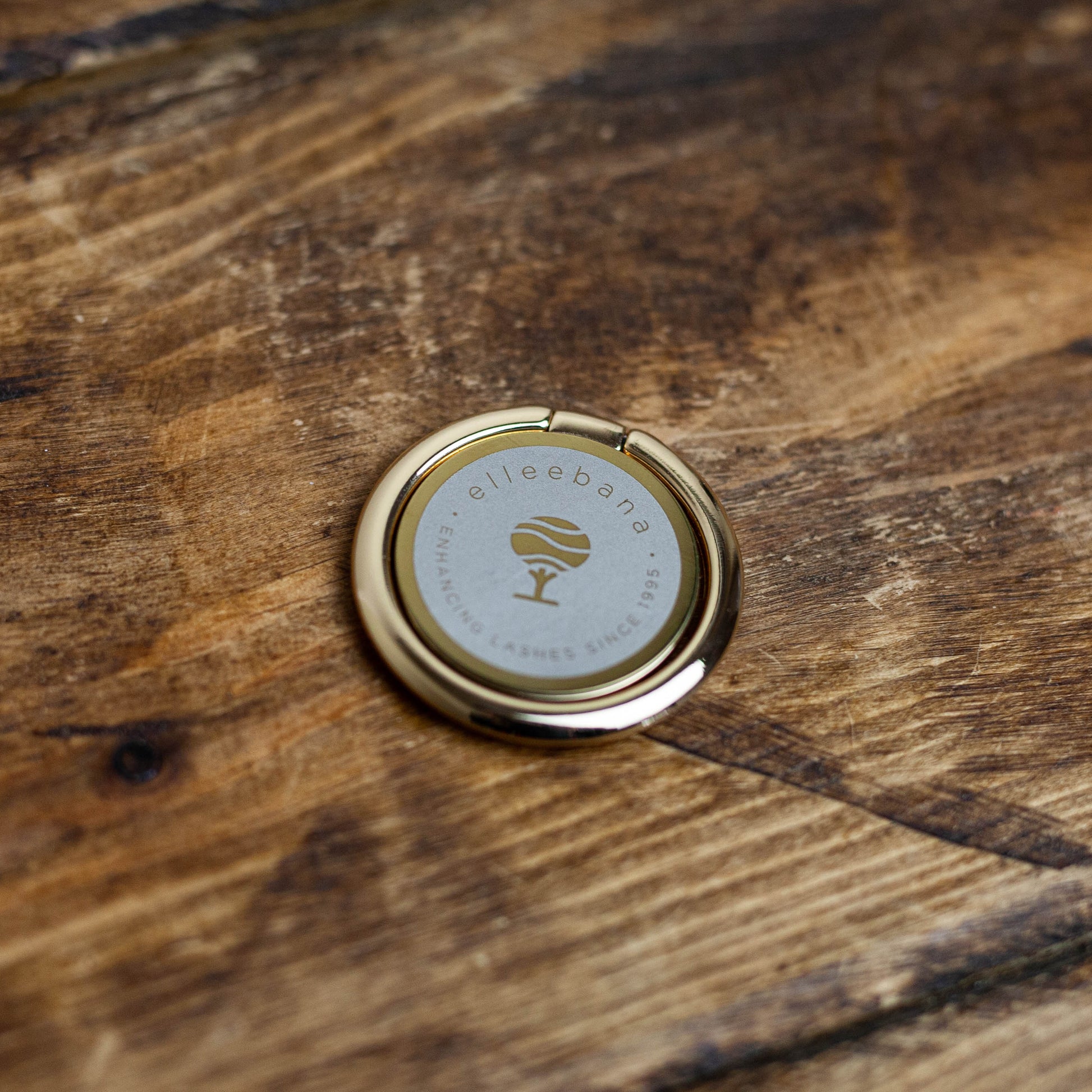 Branded smartphone phone grip and ring holder accessory attached to a phone, designed to secure devices during photography.